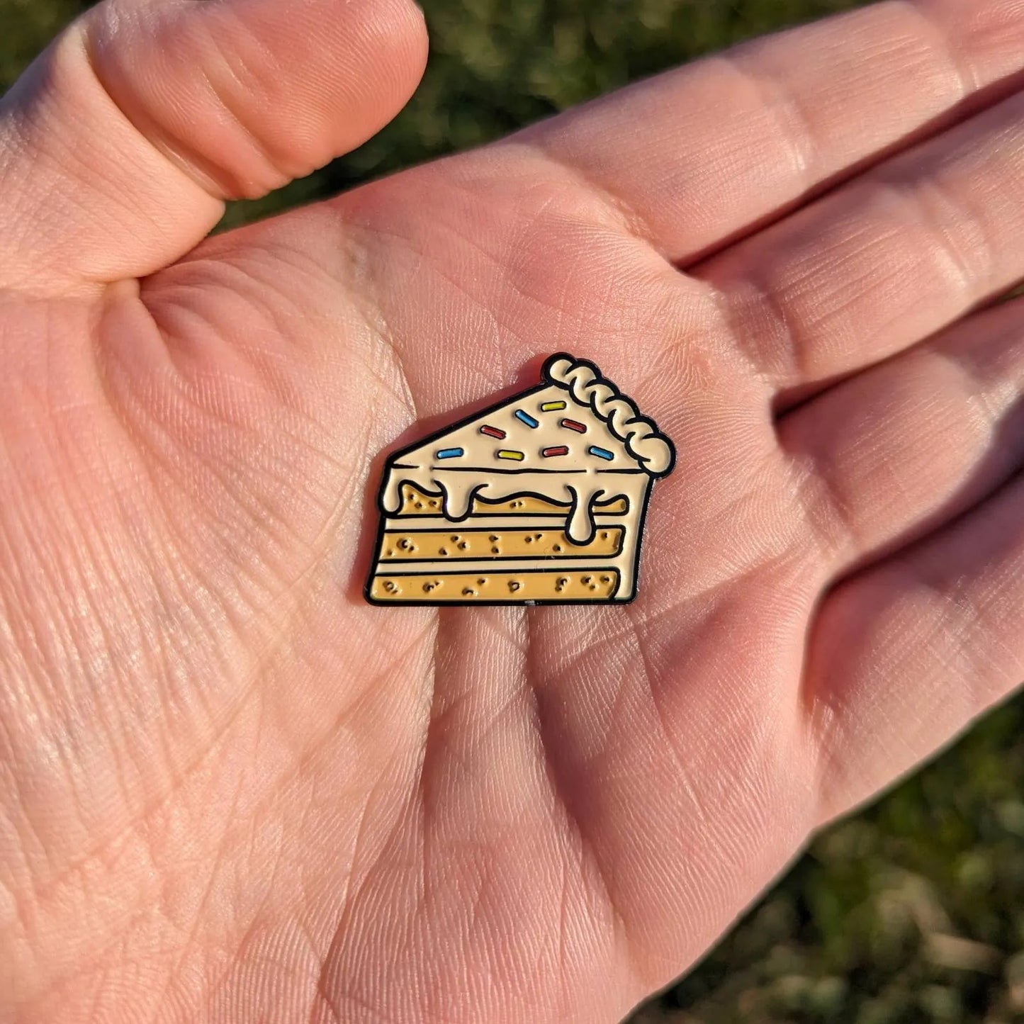 cake golf ball marker with white frosting and rainbow sprinkles in hand