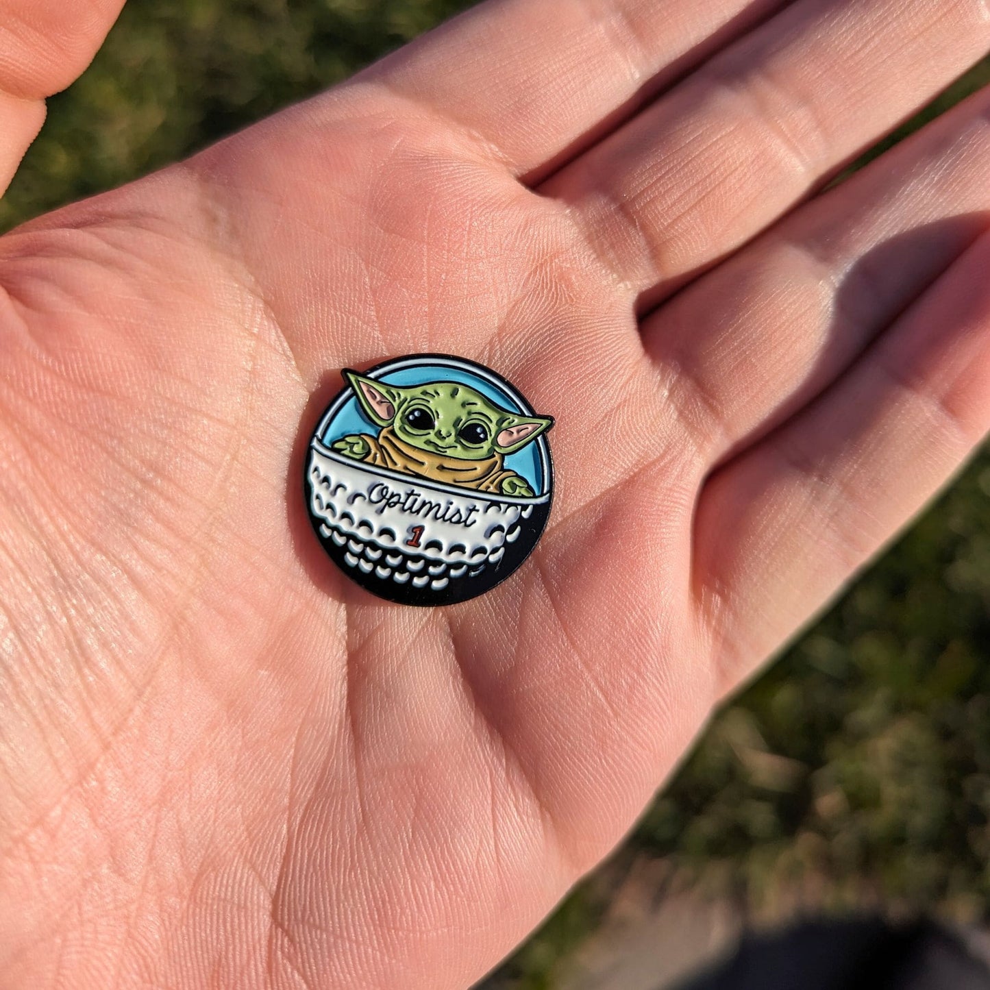golf ball marker of green star baby in golf ball spaceship in hand