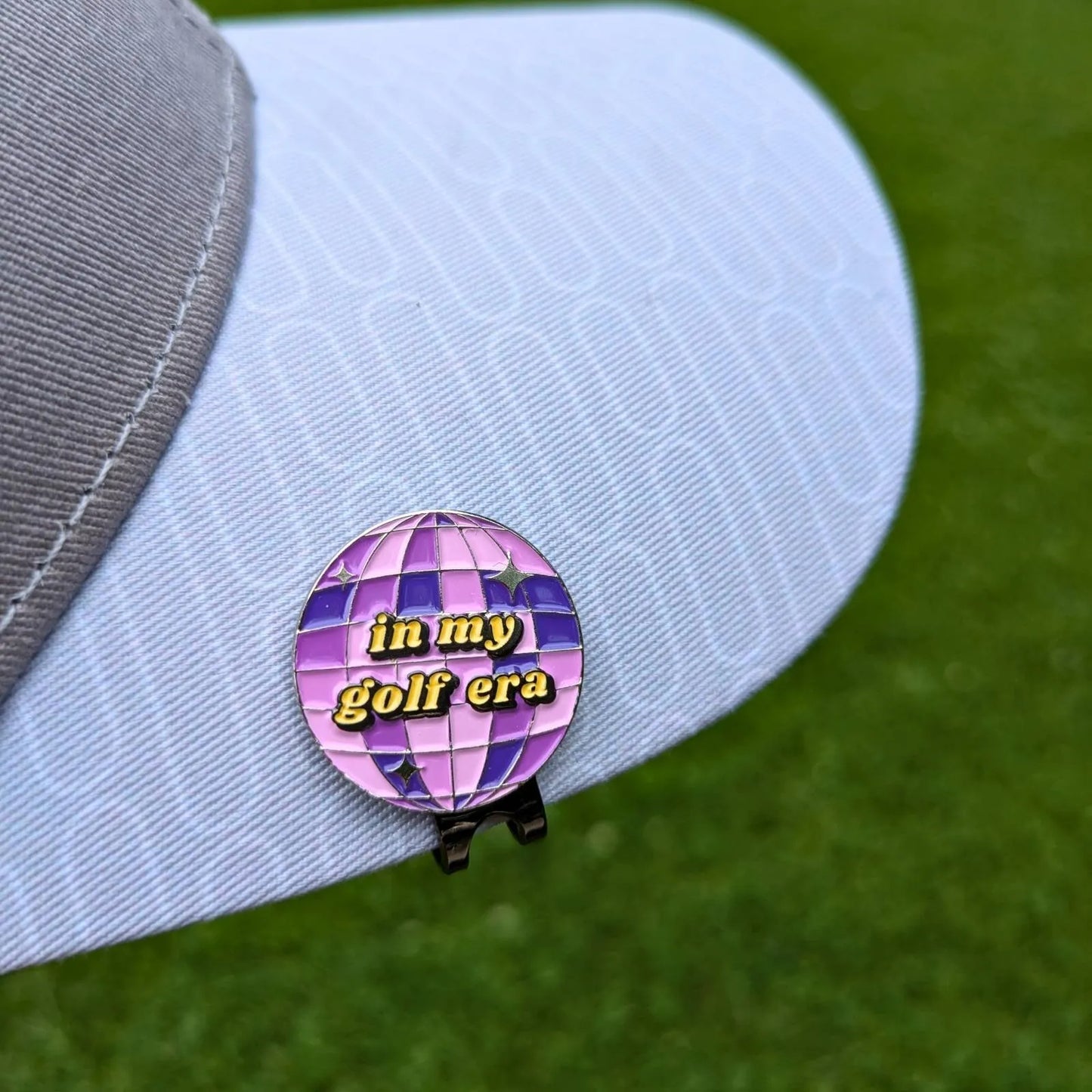 purple swiftie golf ball marker attached to hat with magnetic hat clip